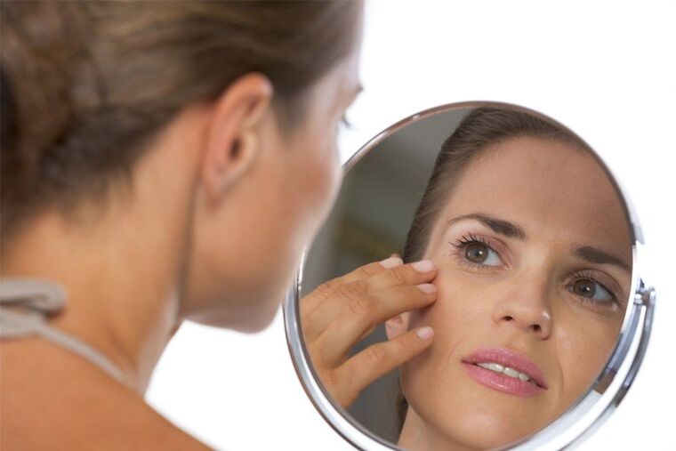 girl looks in the mirror before skin rejuvenation